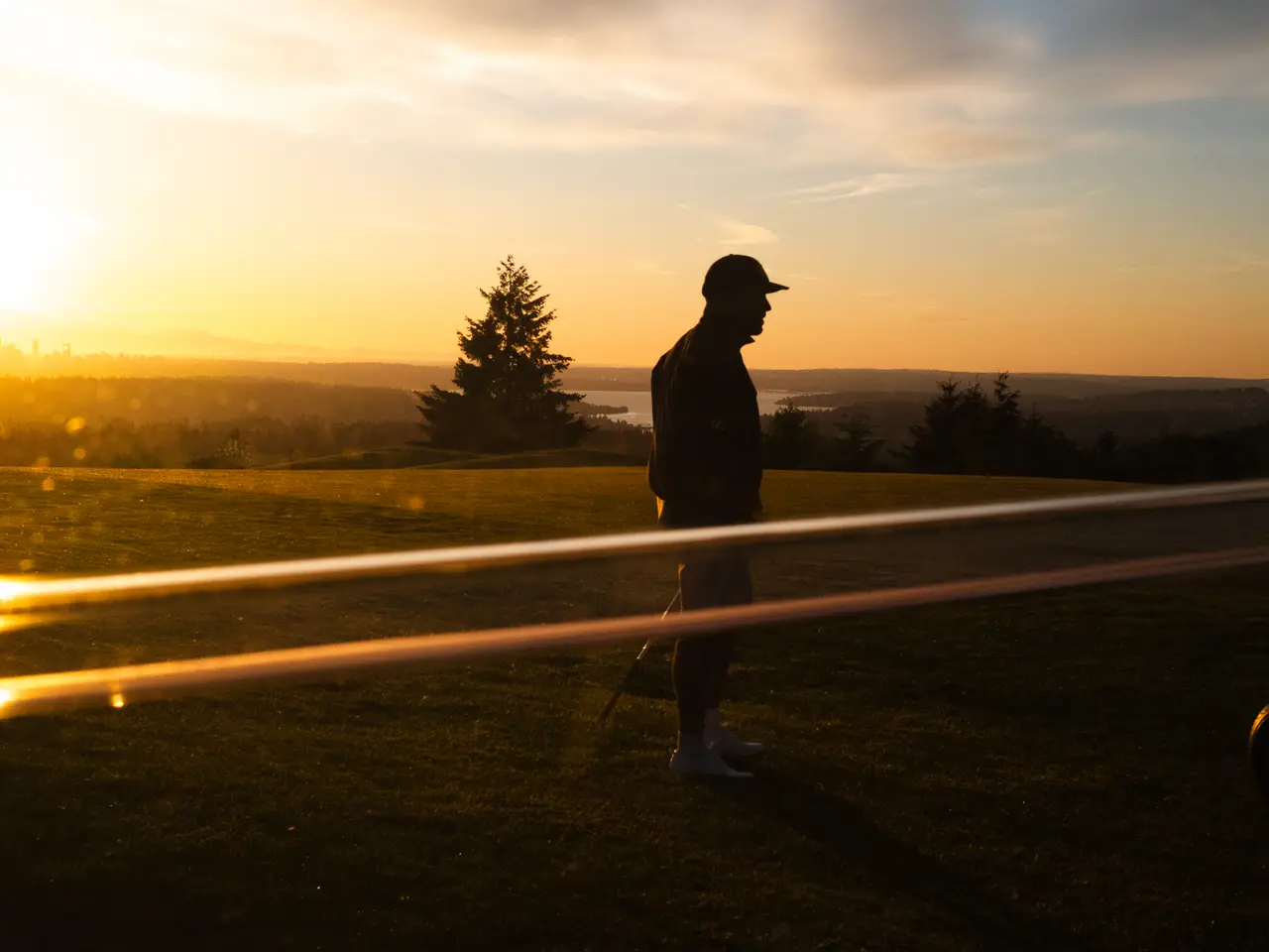 A golfer silhouetted against the sunset as the round winds down