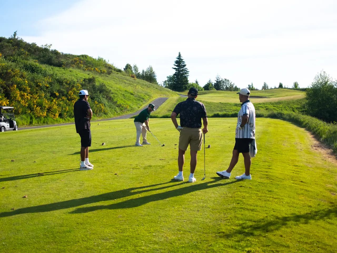 Four players watching a tee shot during an 18 Holes to Home round