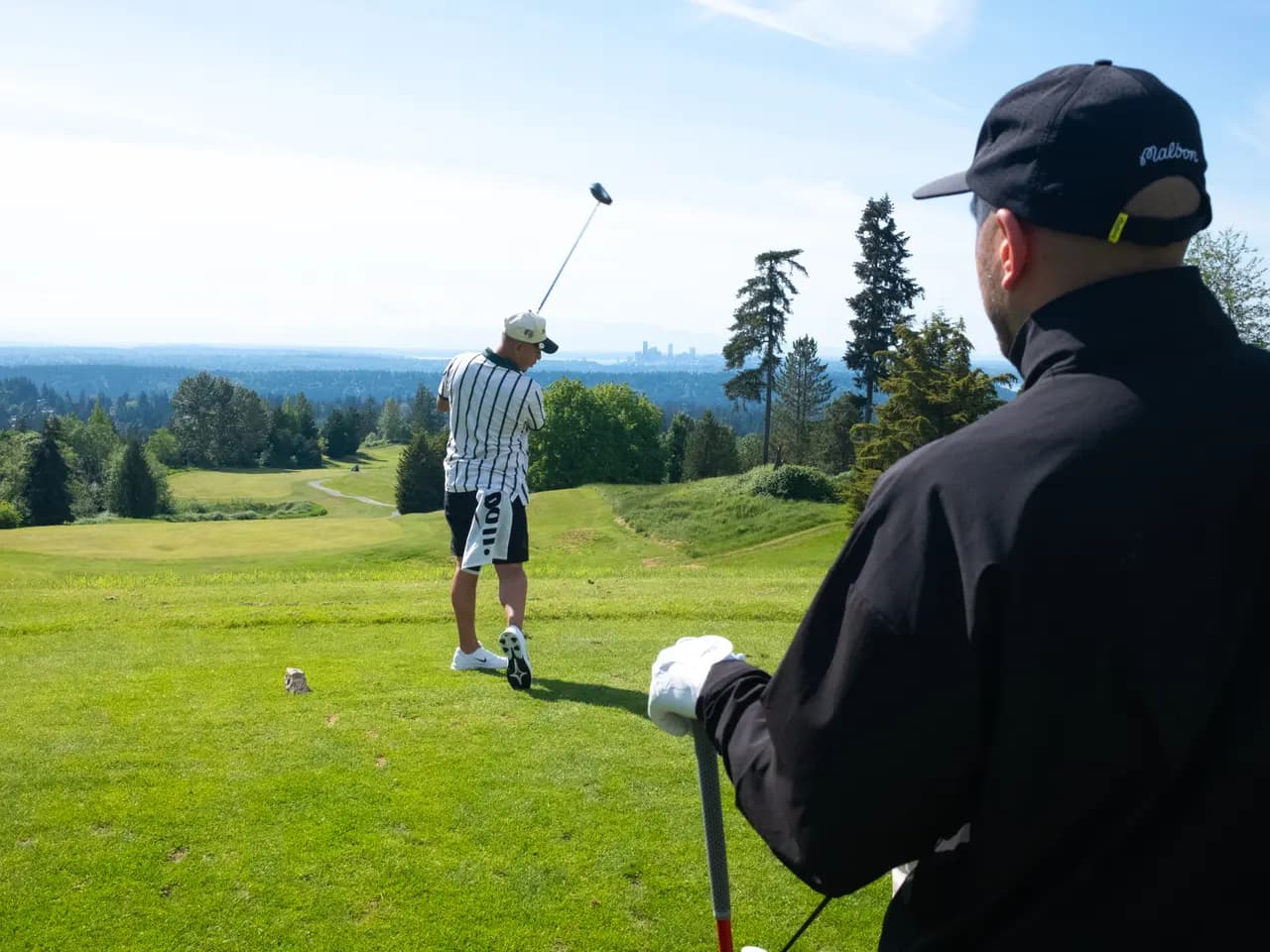 A golfer taking a tee shot while the group watches from the tee box