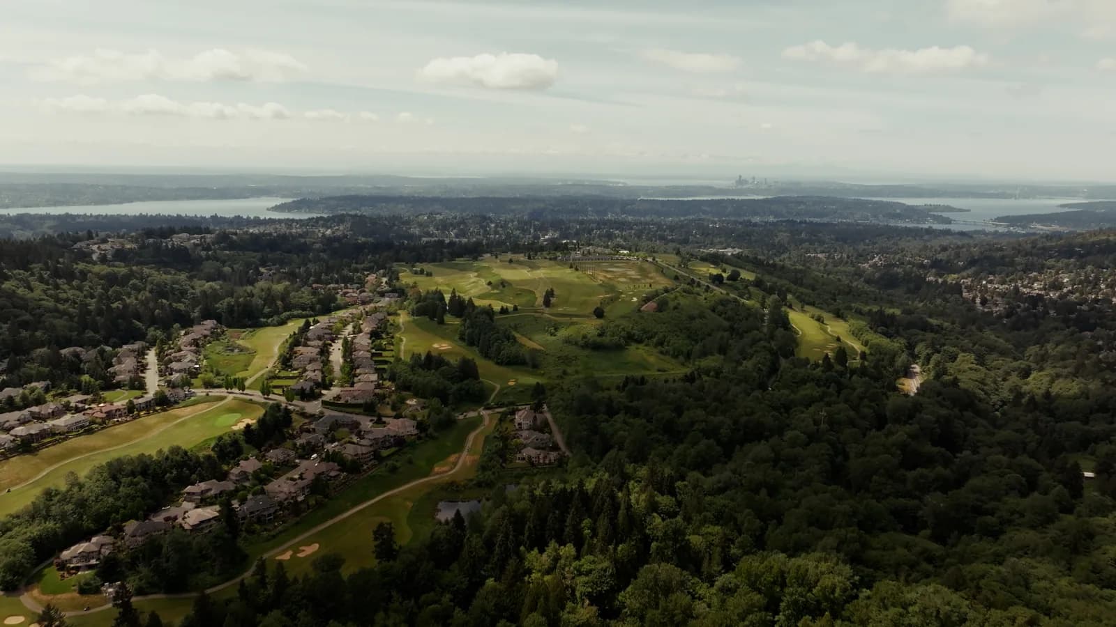Aerial view of golf fairways surrounded by homes and wooded hills