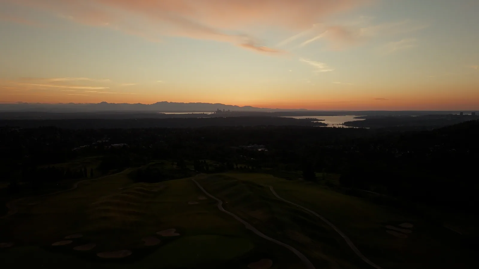 Sunset over a Pacific Northwest golf course with city lights in the distance