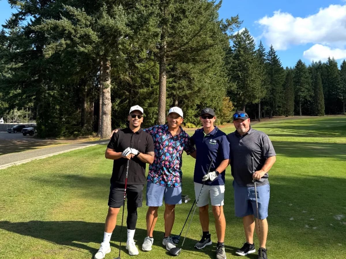 Four golfers standing together on a sunny tree-lined fairway