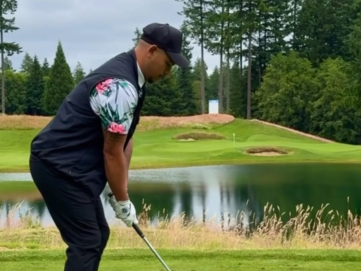 A golfer preparing an approach shot beside a pond on a Pacific Northwest course